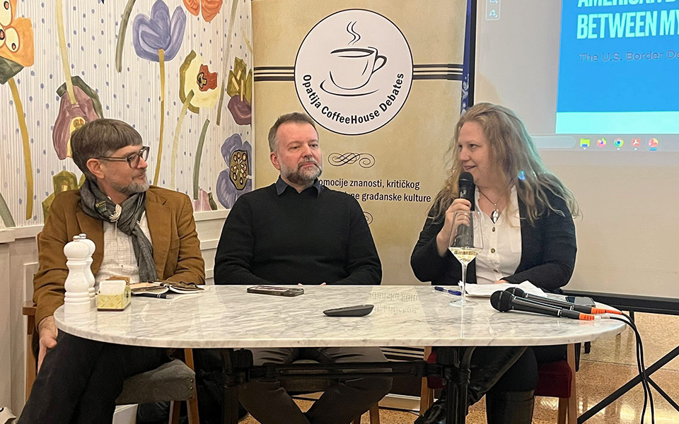 Troje panelista koji sjede za stolom, za njih se vidi Opatija Coffeehouse Debates pingvin